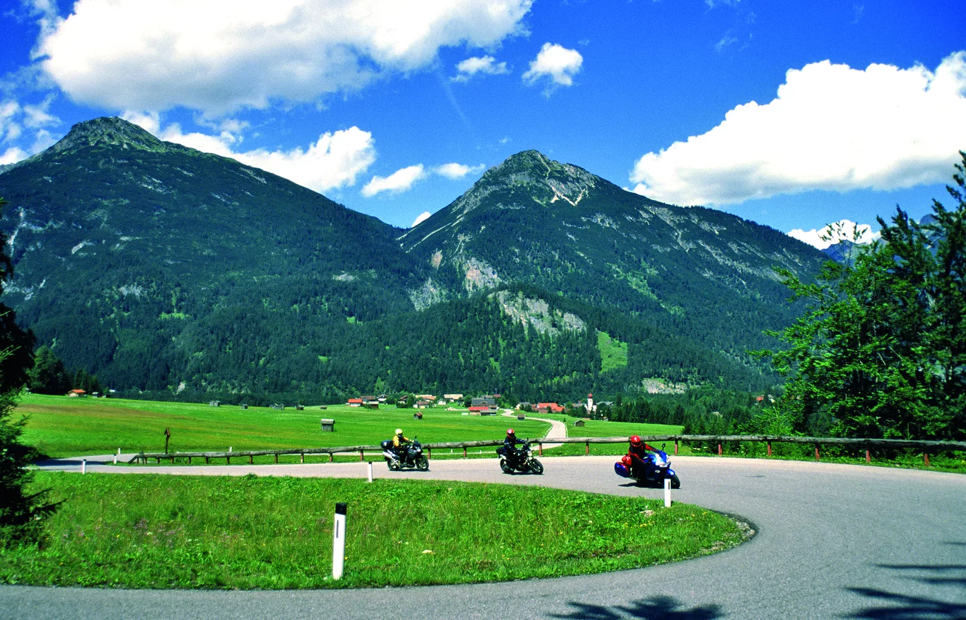 Motorräder in einer Kurve vor weitem Bergpanorama Motorräder in einer Kurve vor weitem Bergpanorama